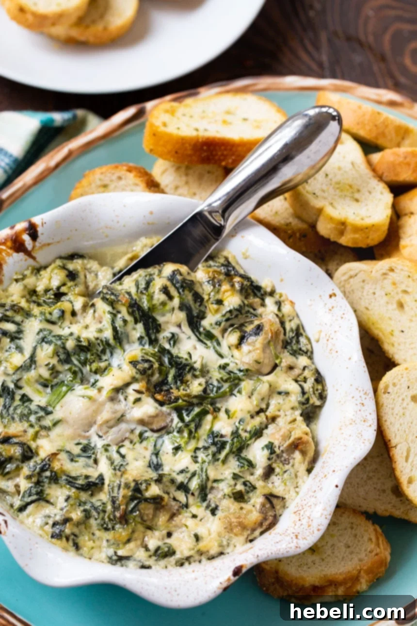 Close-up shot of creamy Oysters Rockefeller Dip with visible spinach and oysters, perfect for dipping.