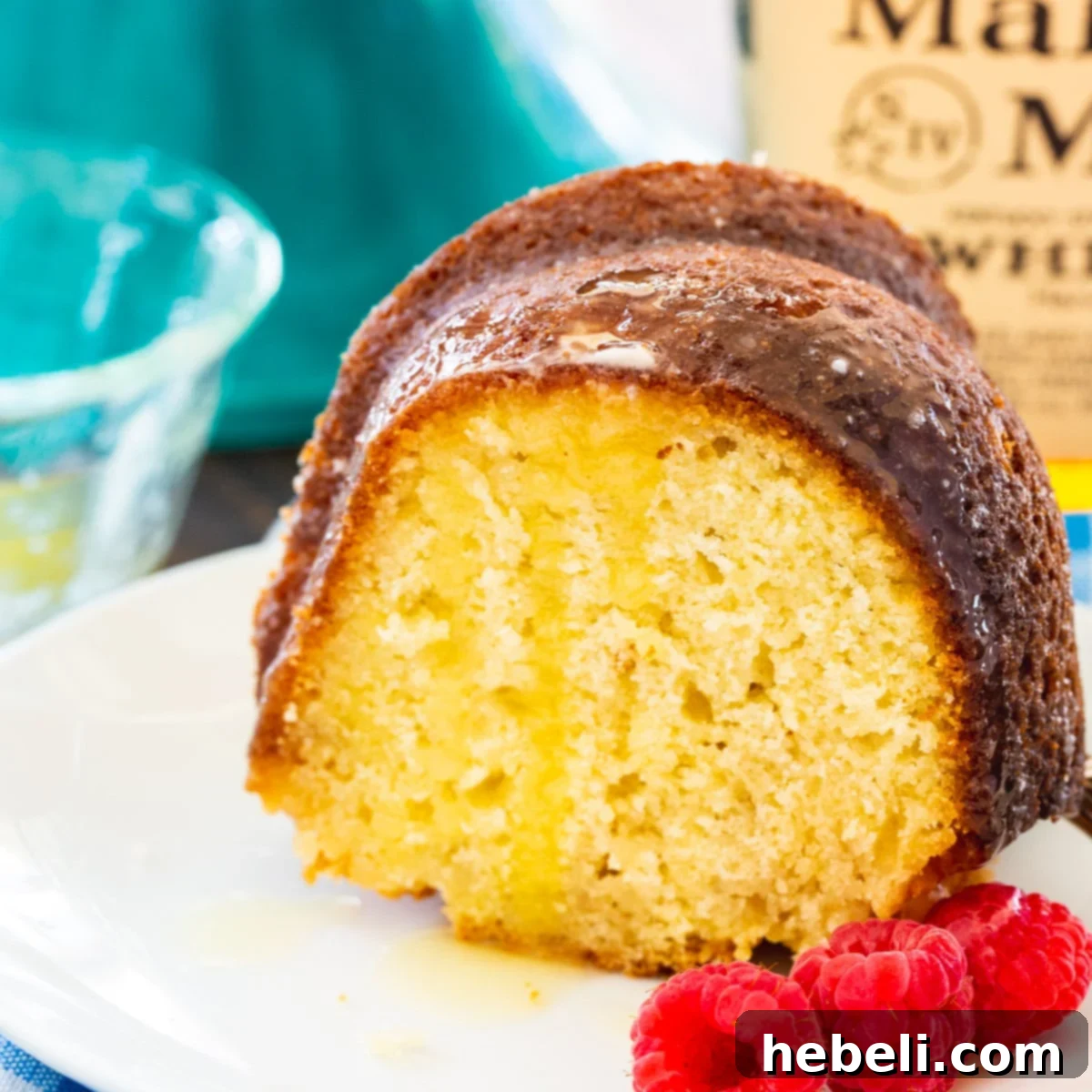 A perfectly sliced piece of Kentucky Bourbon Butter Cake on a white plate, showcasing its moist texture and glistening glaze, ready to be enjoyed.