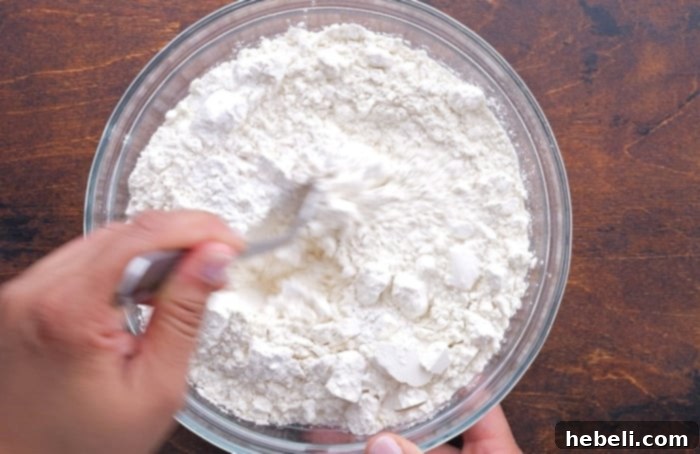 A bowl of dry ingredients (flour, salt, baking powder, baking soda) being whisked.