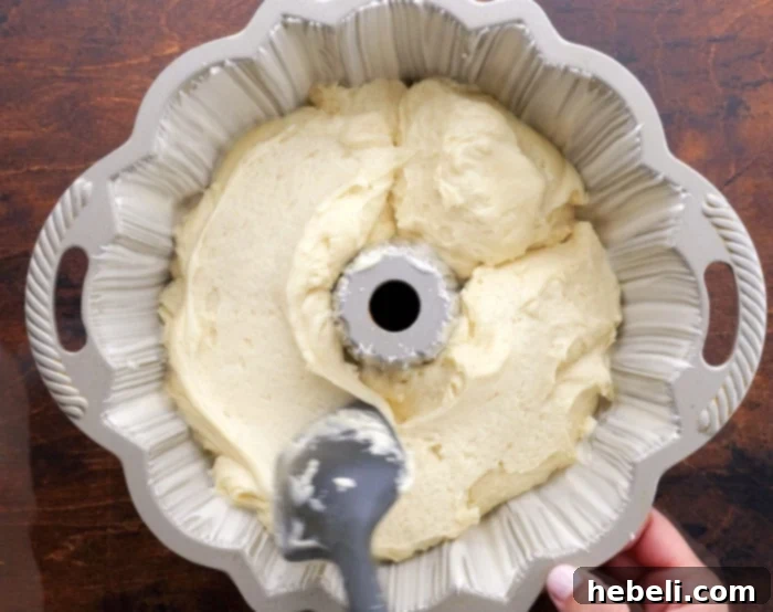 Cake batter evenly spread in a greased Bundt pan, ready for baking.