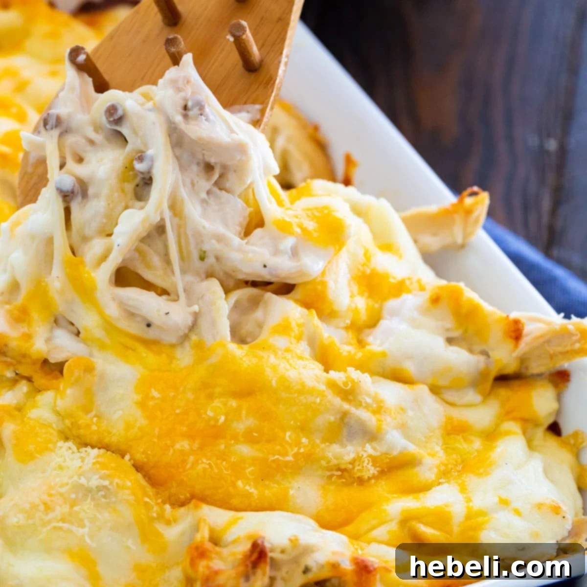 The Ultimate Chicken Alfredo 2 Million Dollar Chicken Alfredo getting scooped out of backing dish. A rich, creamy pasta bake with melted cheese.