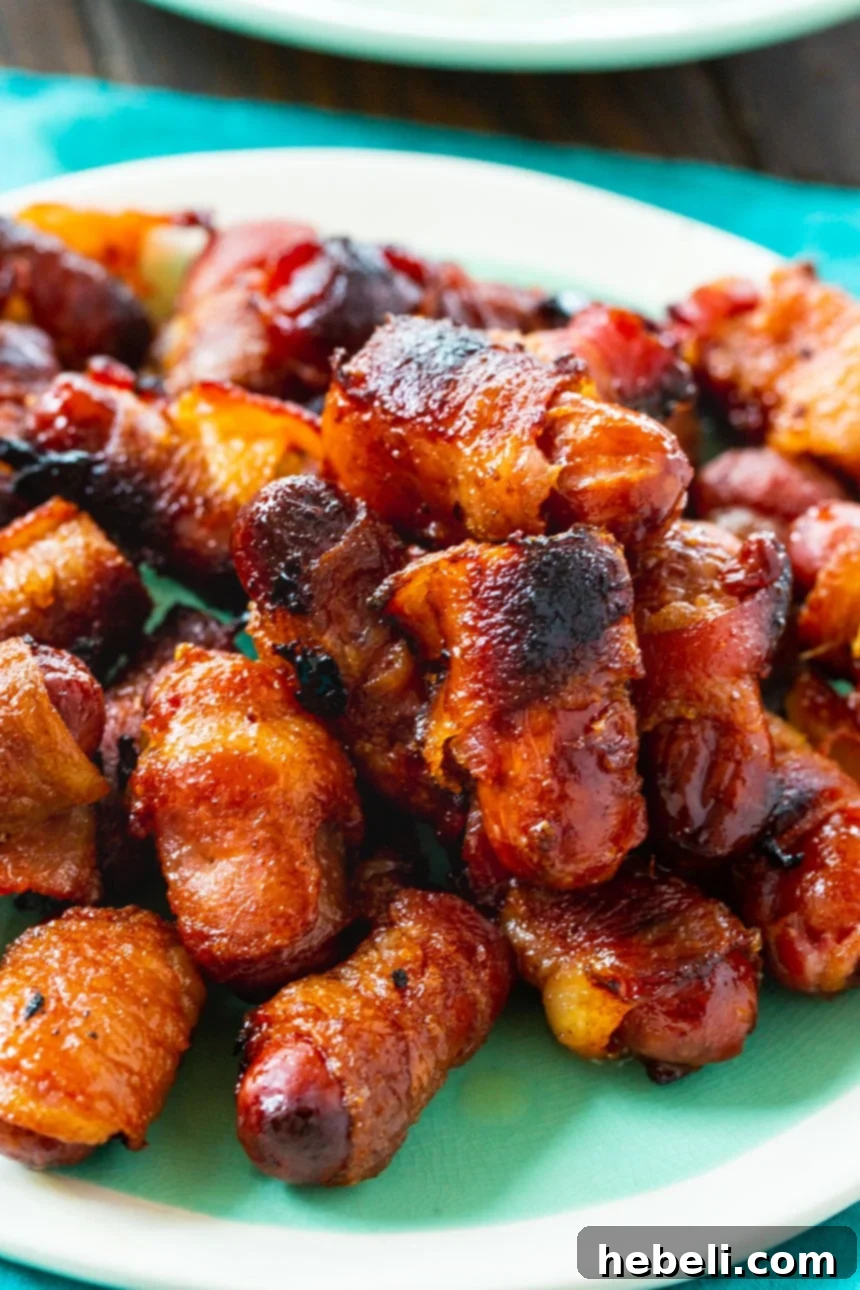 Candied Bacon Smokie Poppers 3 Close-up of Bacon Wrapped Little Smokies glistening with glaze on a baking sheet.