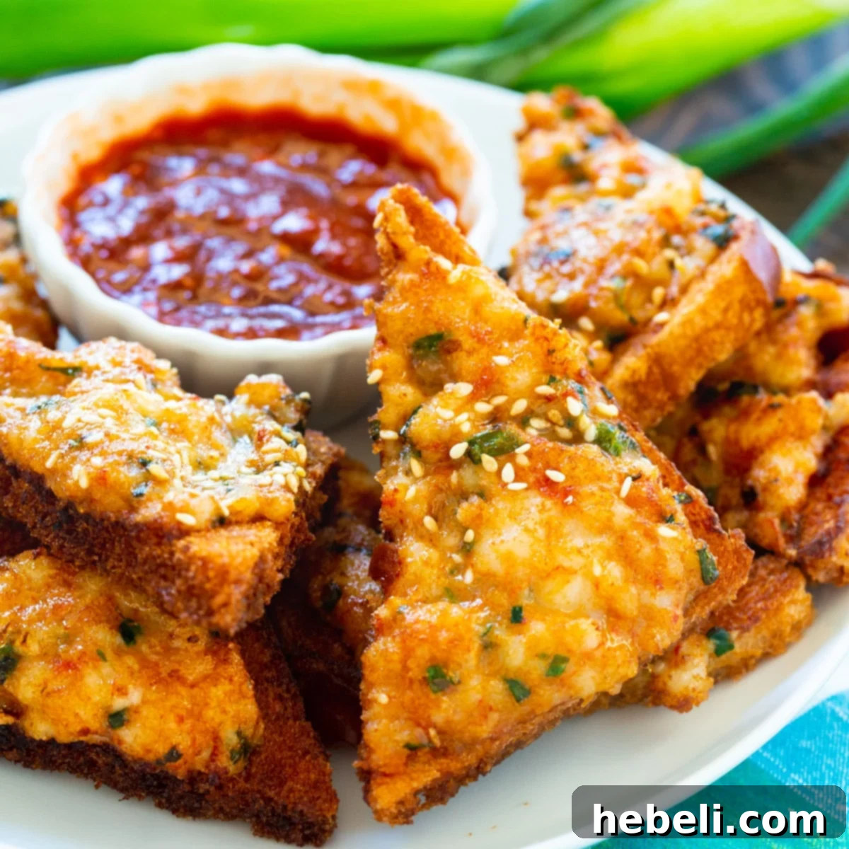 Crispy Homemade Shrimp Toast served on a plate with a side of Chili Garlic Sauce, ready to be enjoyed.