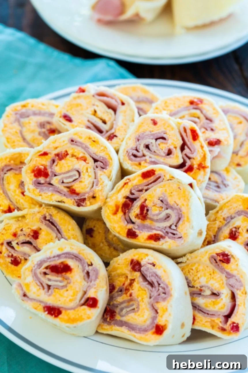 Cheesy Ham & Pimento Swirls 3 Creamy pimento cheese spread and thinly sliced ham layered onto a flour tortilla, ready to be rolled.