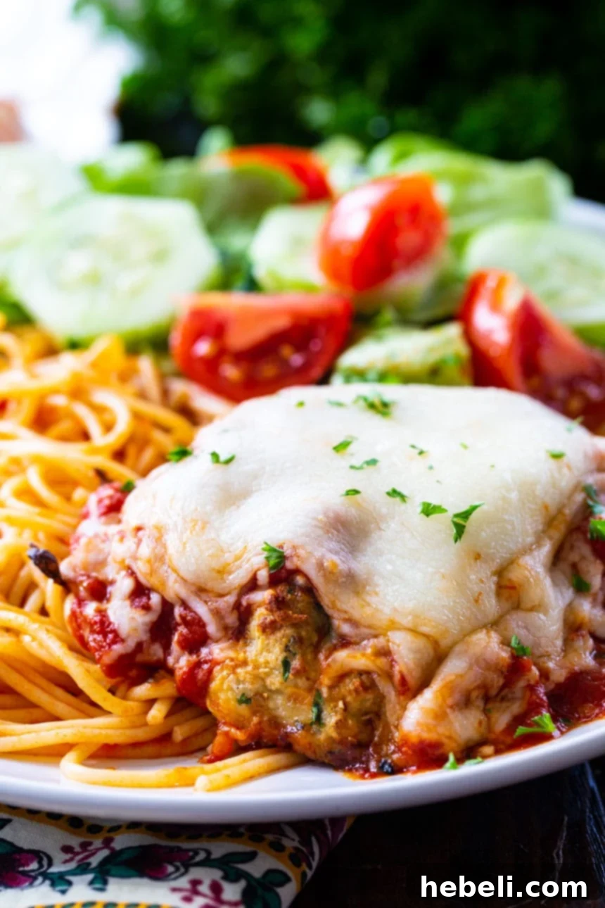 Chicken Patty Parmesan served with spaghetti and garnished with fresh parsley.