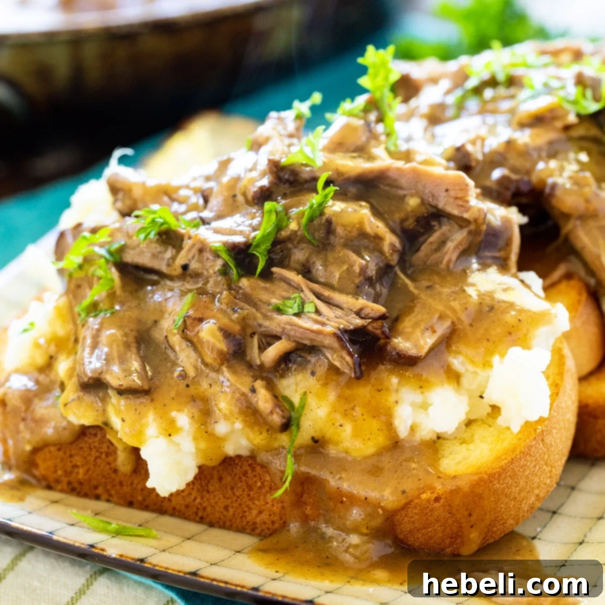 Open-face Hot Beef Sandwiches on a plate, drenched in savory gravy alongside mashed potatoes.