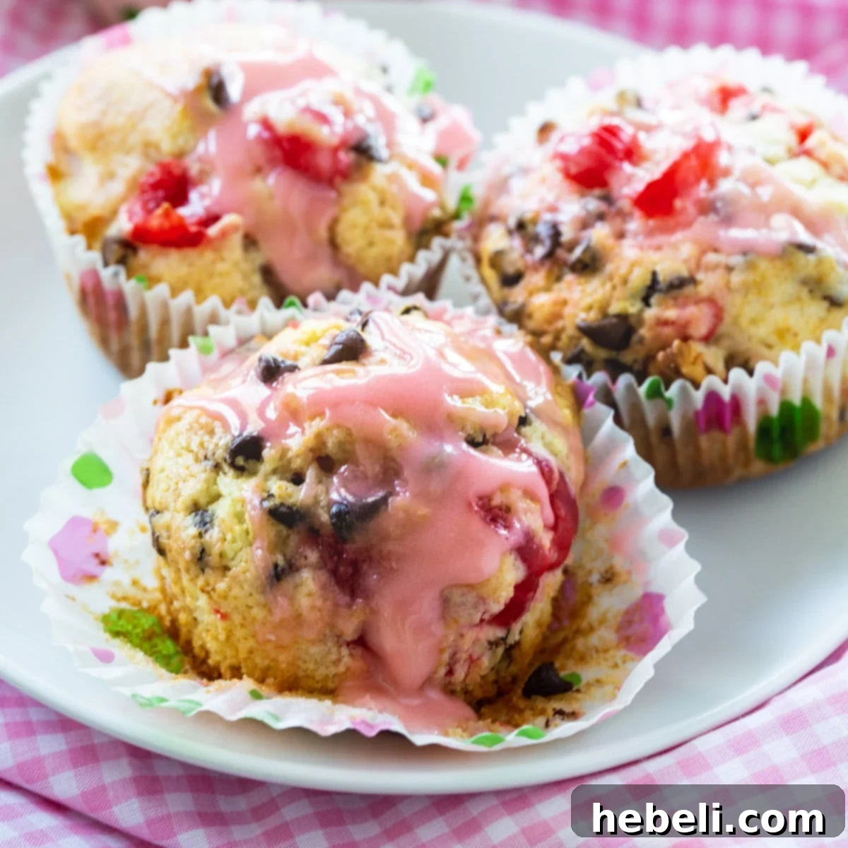 Three Cherry Chocolate Chip Muffins on a plate, showcasing the glaze and visible cherries and chocolate.