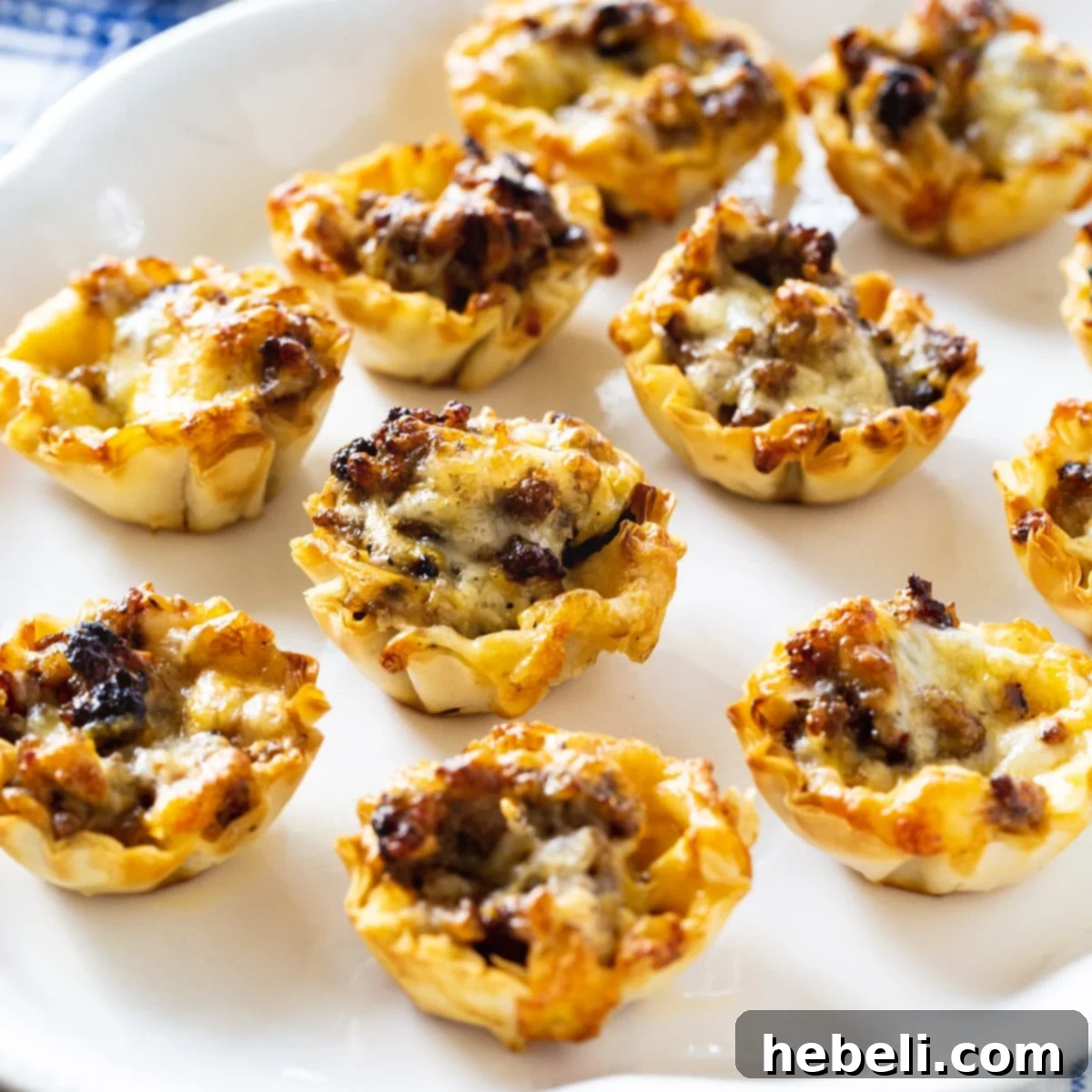A serving platter of golden brown Sausage Ranch Phyllo Cups, showcasing their flaky crust and savory filling.