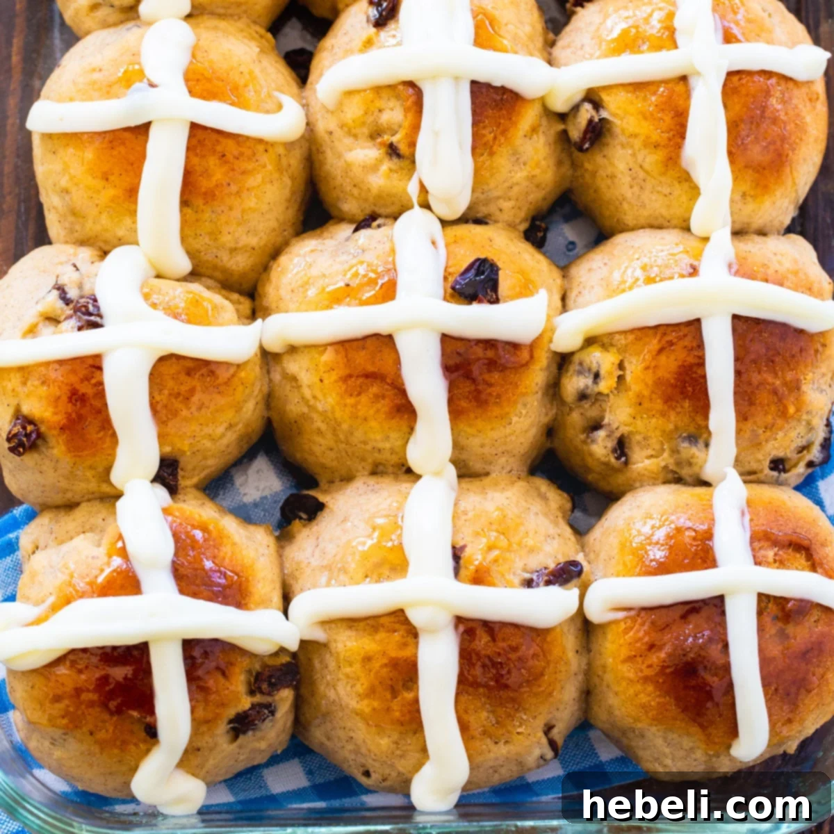 Nine Hot Cross Buns on a baking sheet, golden brown and perfectly glazed.