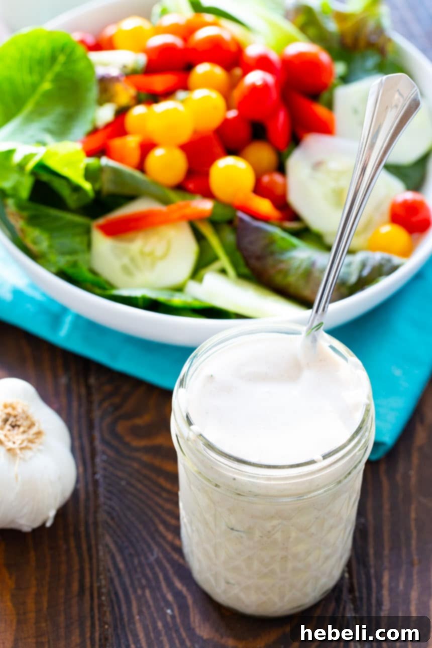 Buttermilk Garlic Dressing drizzled over a fresh green salad with tomatoes and other vibrant vegetables.