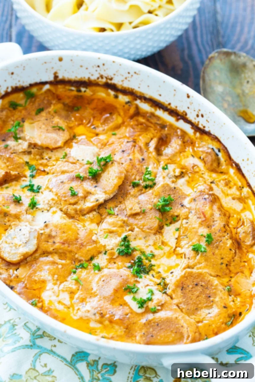 Chicken Paprikash in an oval baking dish, glistening with rich, creamy sauce.
