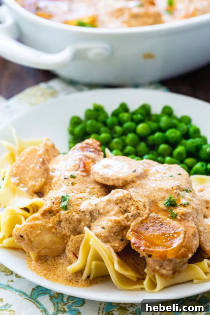 Chicken Paprikash served over egg noodles with fresh green peas, ready to be enjoyed.