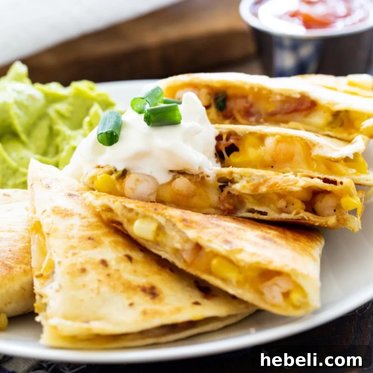 Sizzling Shrimp, Bacon and Corn Quesadillas 2 Crispy Shrimp, Bacon, and Corn Quesadilla on a plate with vibrant guacamole and fresh salsa, ready to be enjoyed.