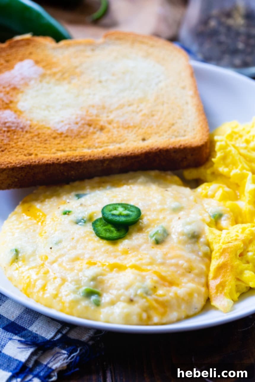 Jalapeno Cheddar Grits Delight 4 Serving of Jalapeno Cheddar Cheese Grits in a white bowl, with a spoon digging in.