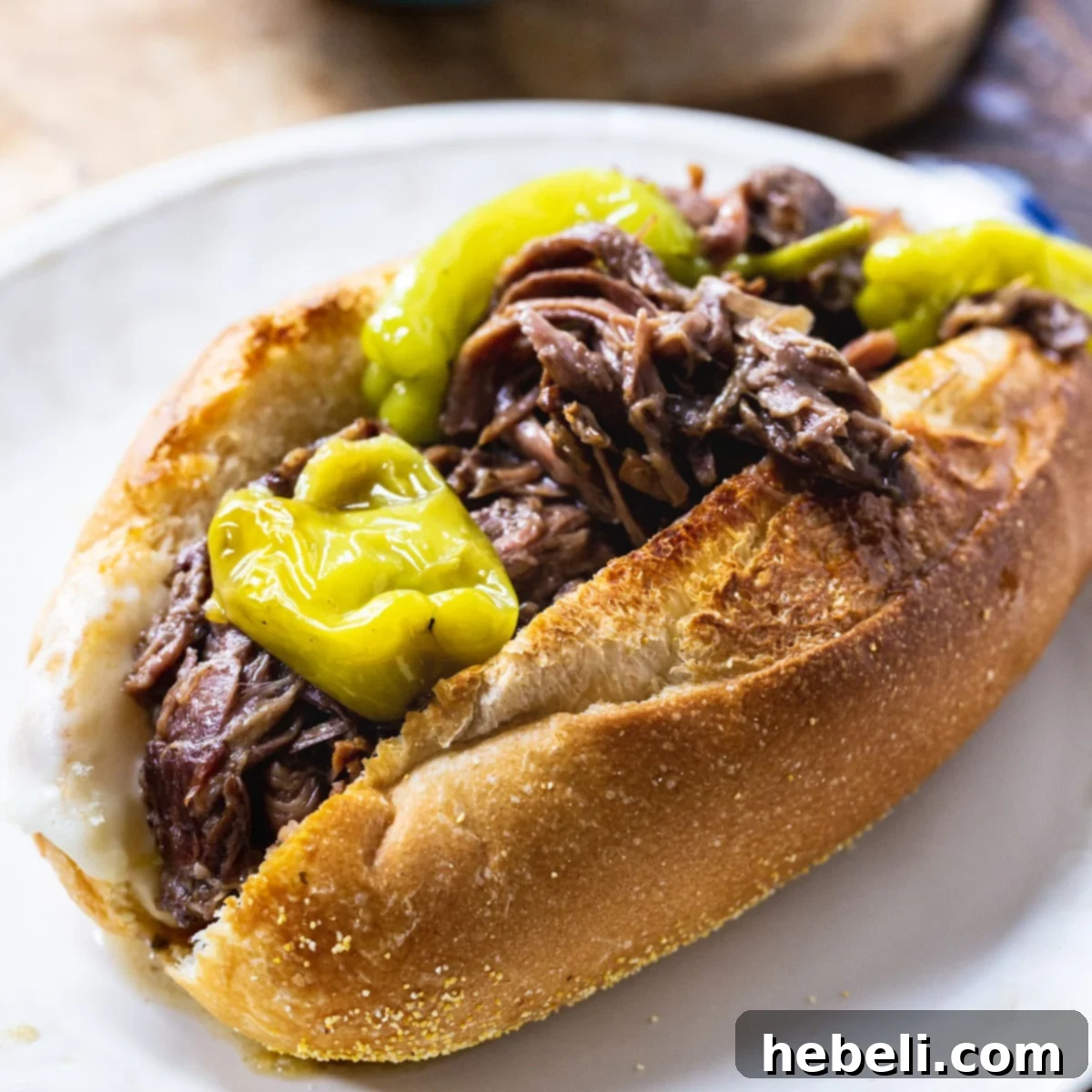 Slow Cooker Mississippi Beef served in a toasted sub roll with provolone cheese and mayonnaise.