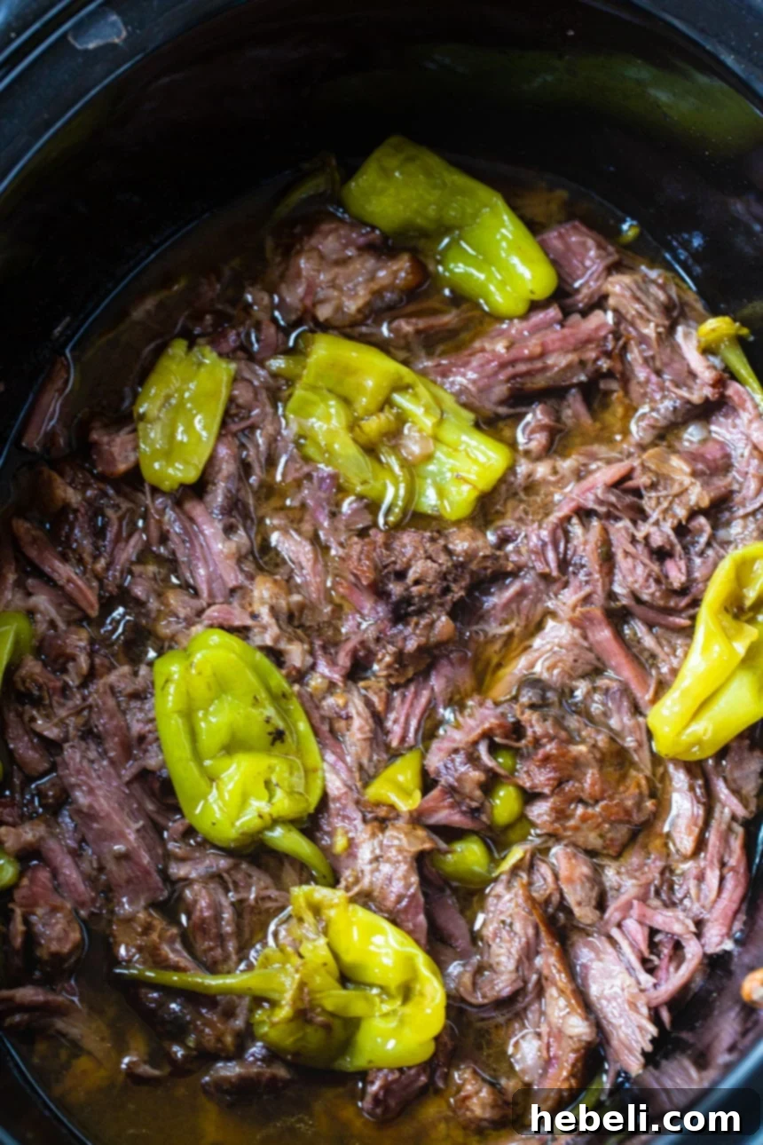 Close-up of shredded Slow Cooker Mississippi Beef in a slow cooker, ready to be served.