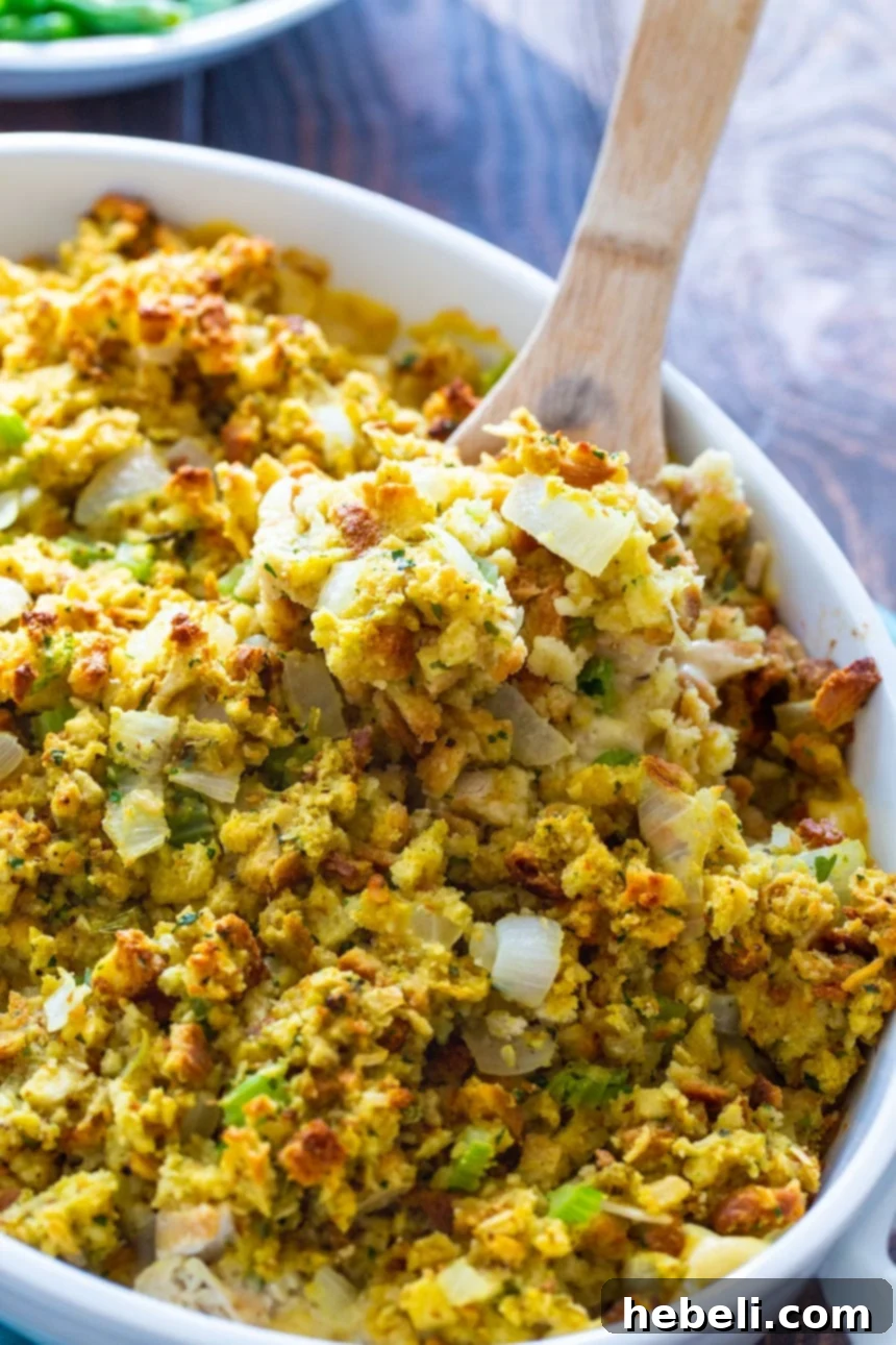 Wooden spoon scooping a generous portion of chicken stuffing casserole out of a baking dish.