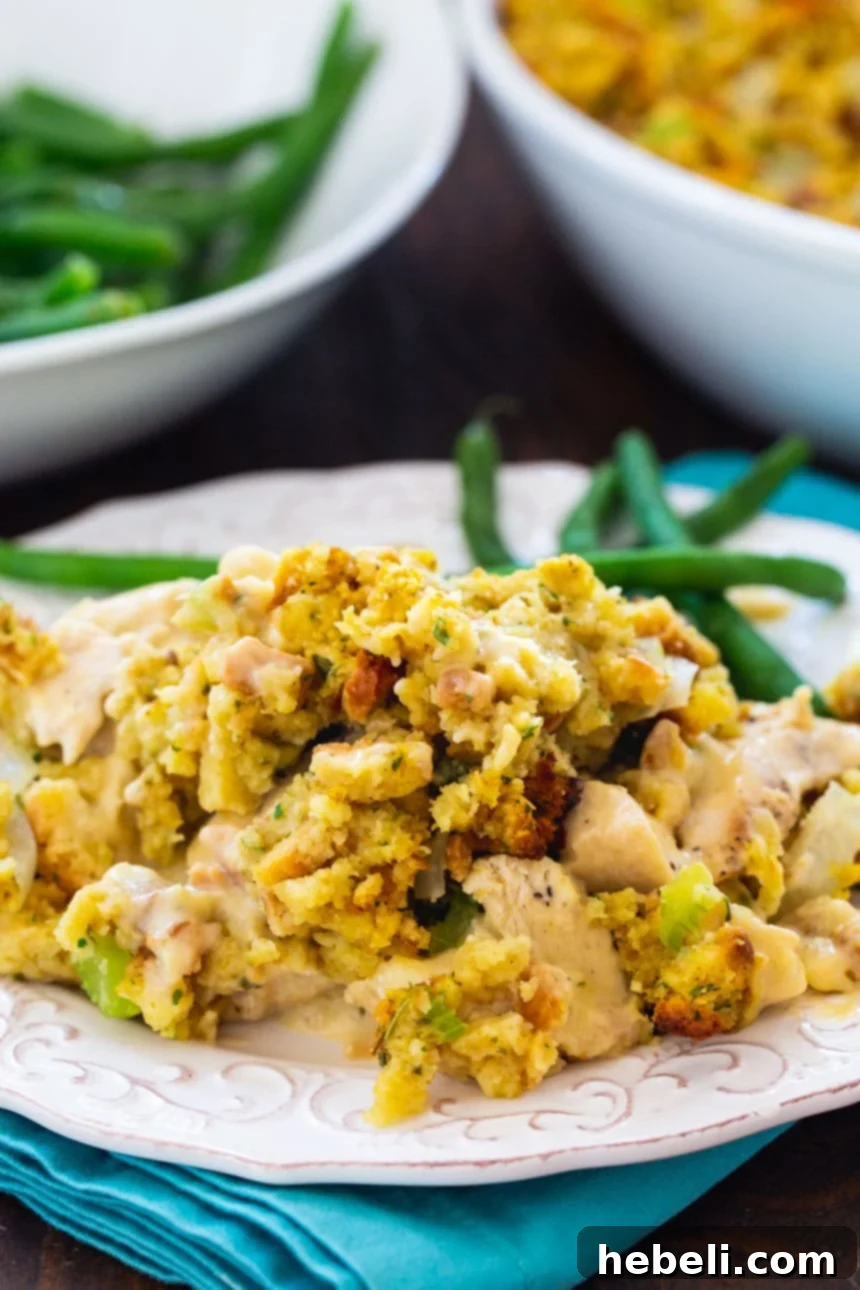 A generous serving of So Easy Chicken Stuffing Casserole on a white plate, accompanied by vibrant green beans.