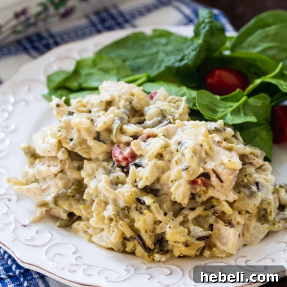 A generous serving of Chicken Wild Rice Casserole on a white plate, accompanied by a fresh green salad.