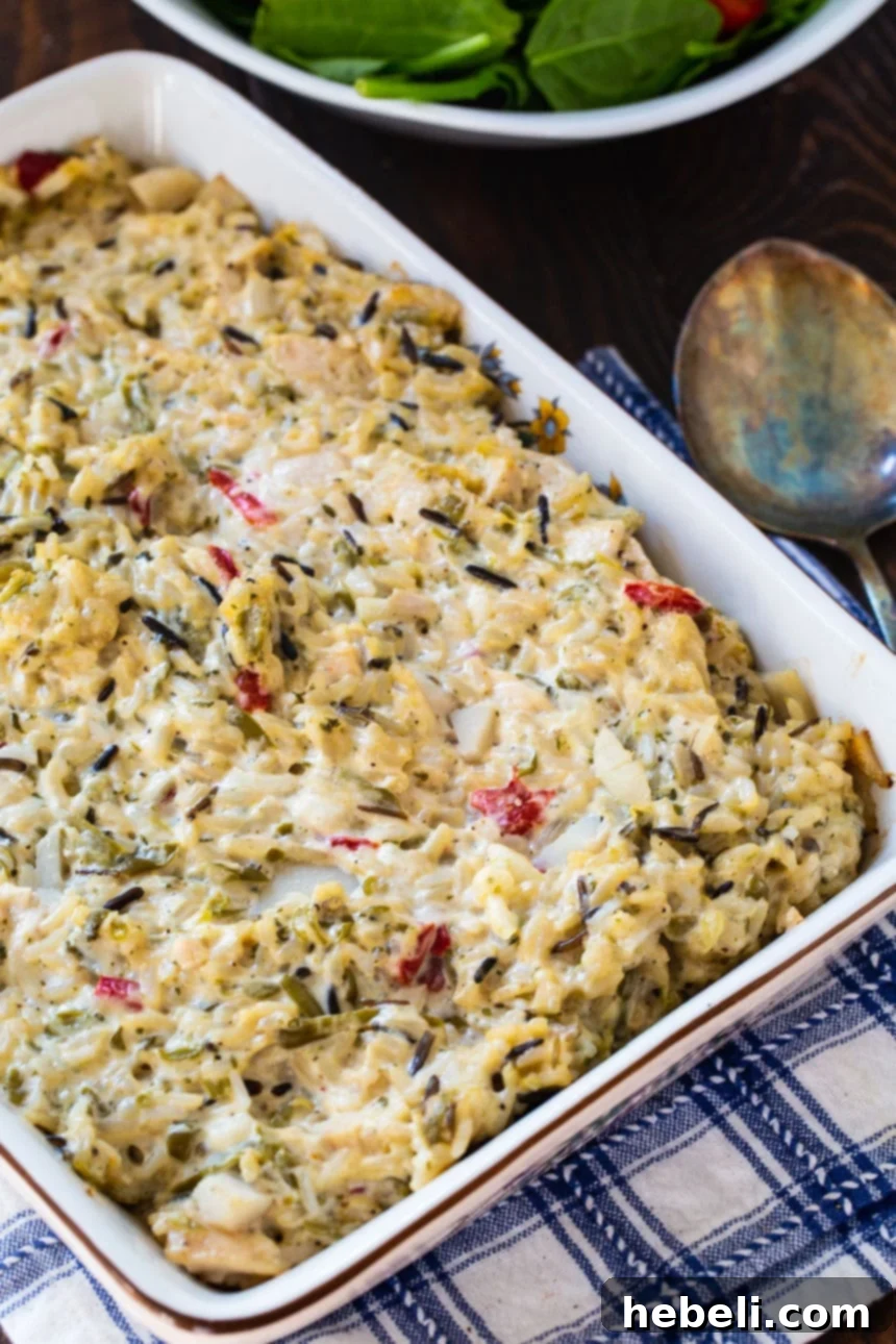 A close-up view of the Chicken Wild Rice Casserole baking in a glass dish, showing its golden-brown topping.