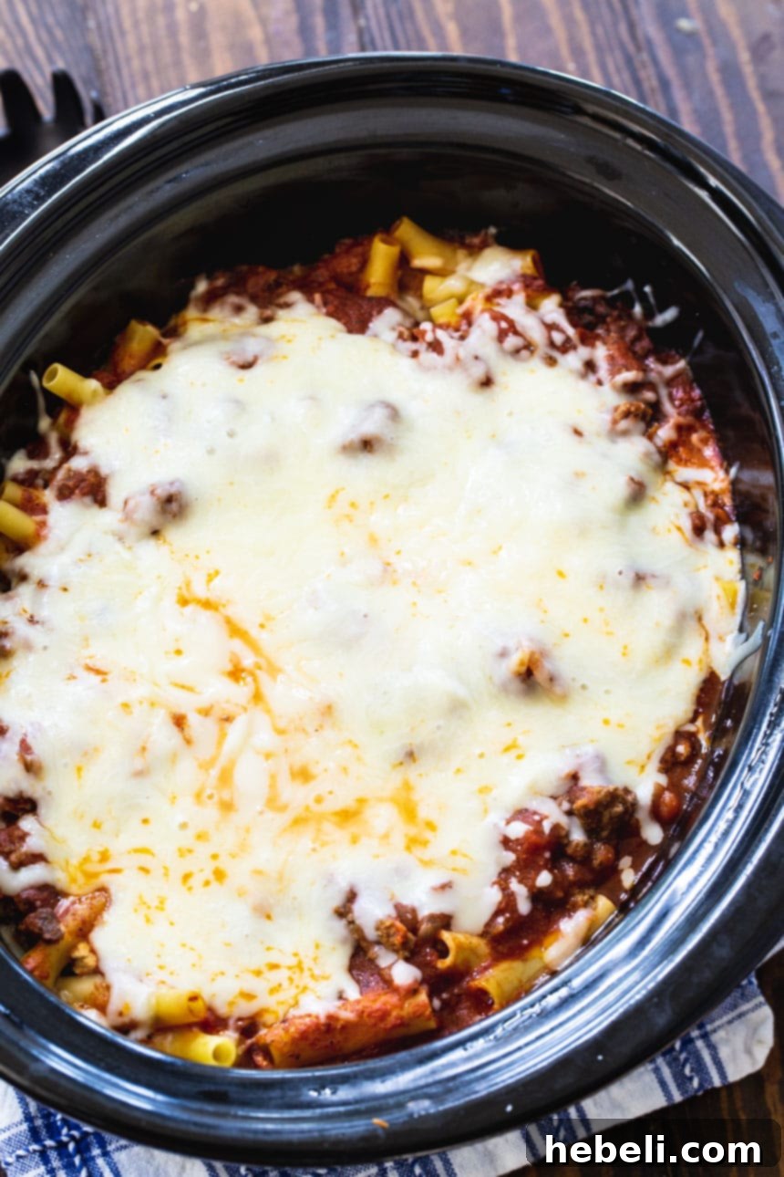 Hearty Baked Ziti cooking in a slow cooker, topped with melted cheese.