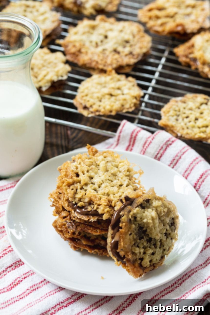 Freshly baked Florentine cookies cooling on a wire rack, with more stacked on a plate in the background.