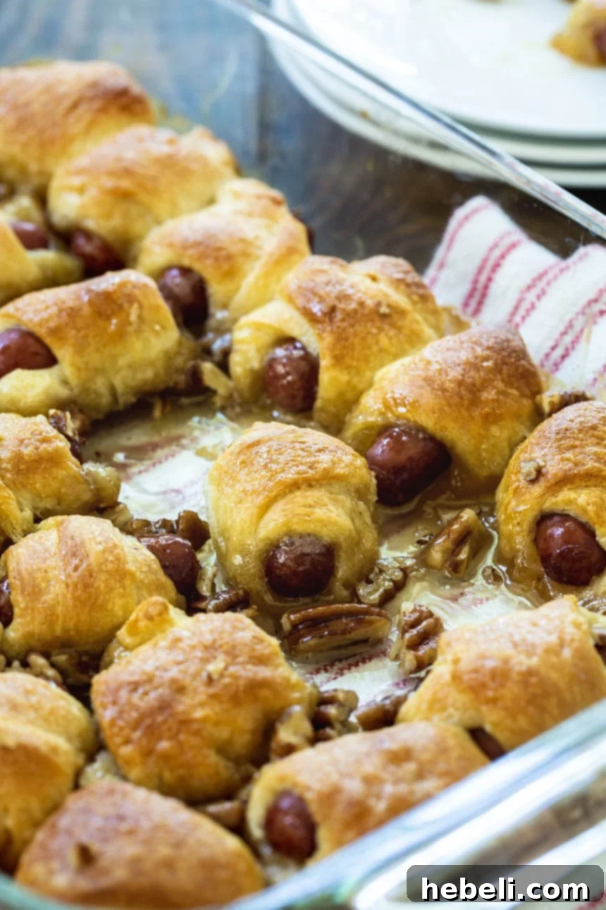 Little Smokies wrapped with crescent rolls in a baking dish before baking.