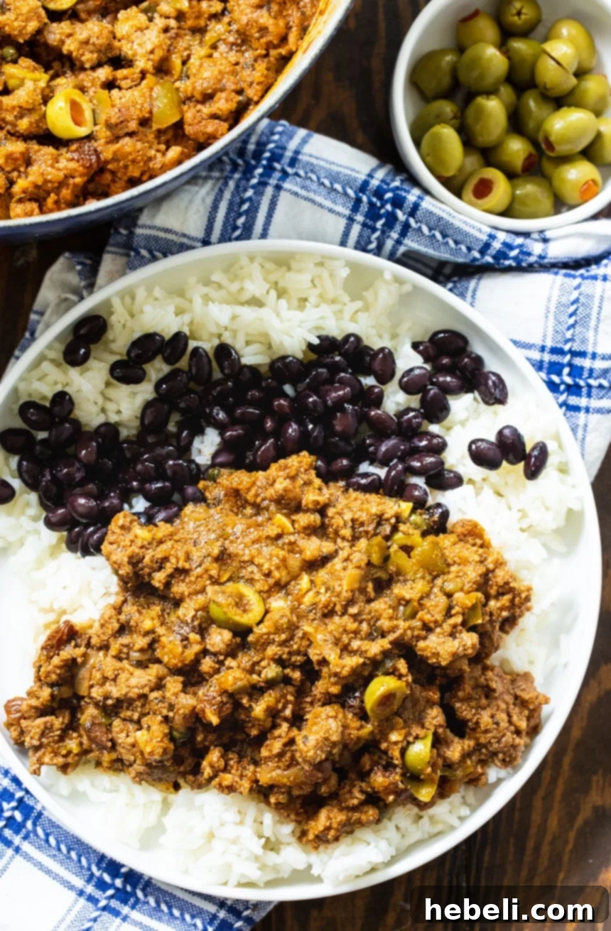 Flavorful Homemade Picadillo 3 Cuban Picadillo served elegantly with fluffy white rice and a side of seasoned black beans.