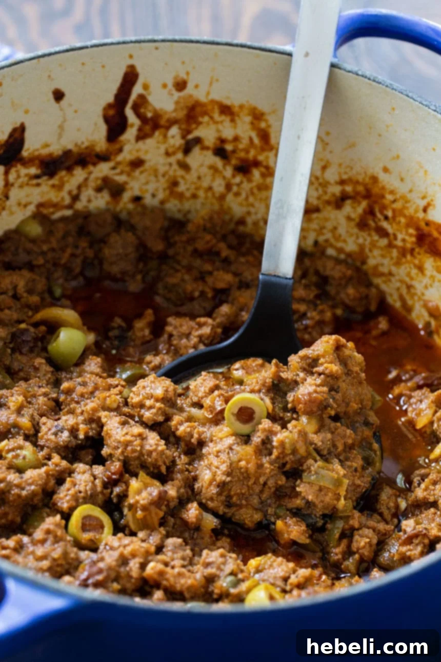 Flavorful Homemade Picadillo 4 Close-up shot of rich ground beef Picadillo simmering in a Dutch oven, showcasing its texture and vibrant colors.