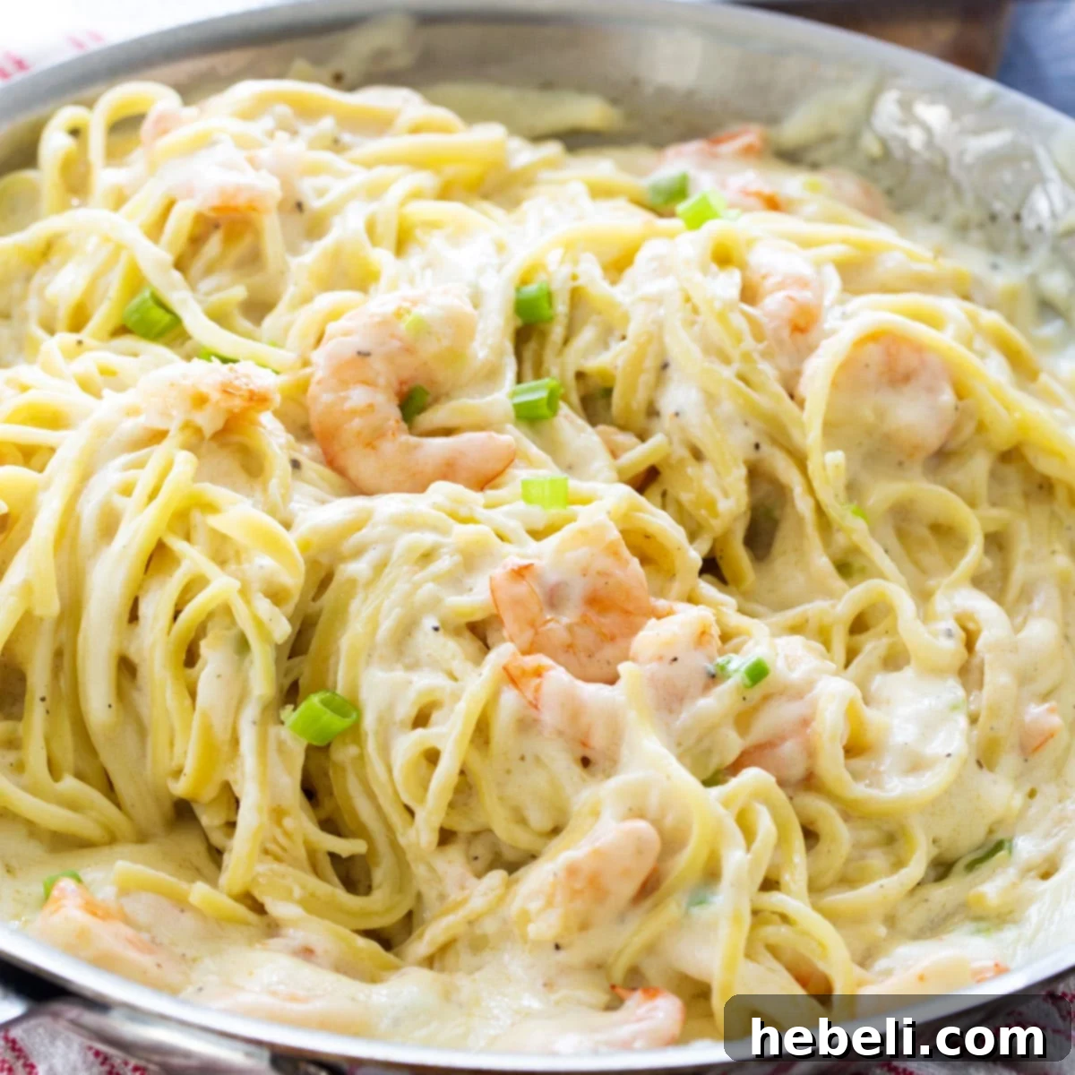 A large skillet filled with tantalizing Cheesy Garlic Shrimp Alfredo, ready to be served.