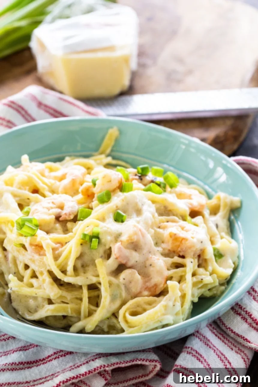 A vibrant blue bowl generously filled with creamy Cheesy Garlic Shrimp Alfredo, garnished with fresh herbs.