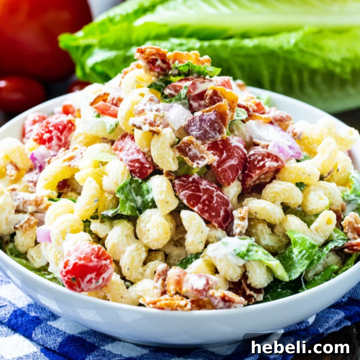 BLT Pasta Salad in a bowl, featuring a mix of pasta, crispy bacon, red tomatoes, and green romaine lettuce.