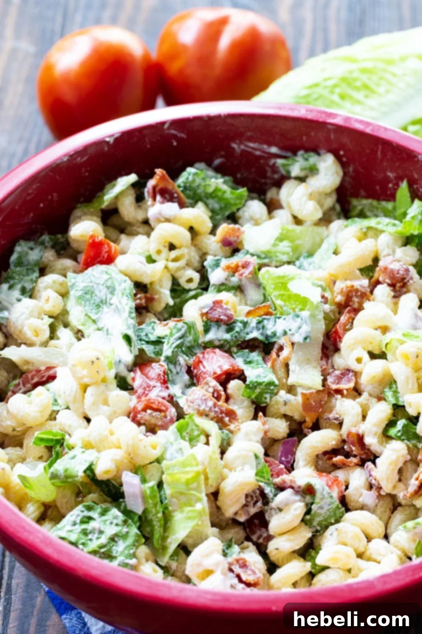 BLT Pasta Salad in a large red bowl, showcasing a vibrant mix of ingredients, ready to be served.