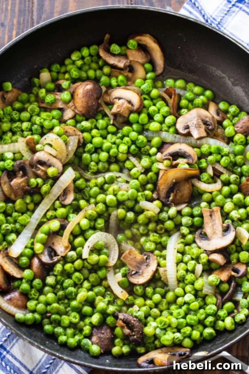 Buttered Peas and Mushrooms served in a large skillet, ready to be dished out.