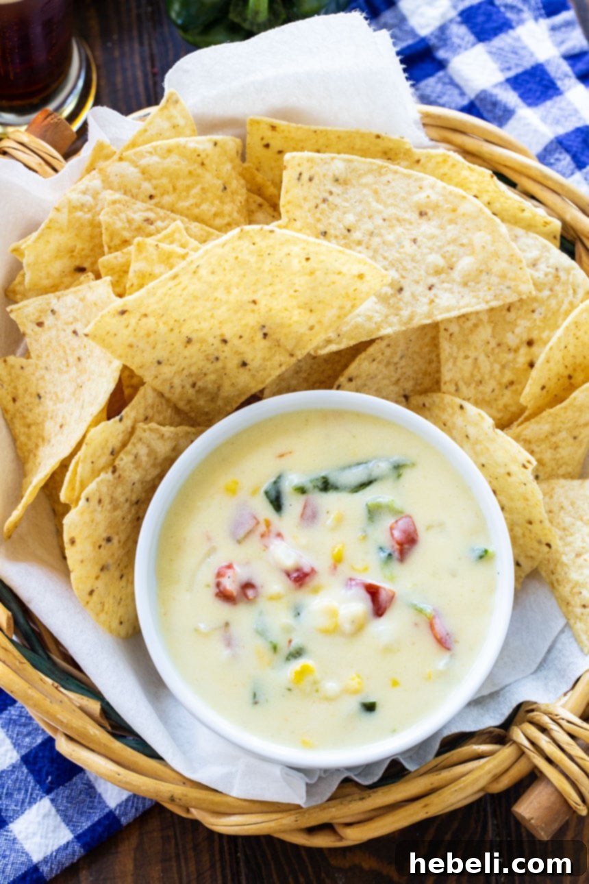 Smoky Poblano and Sweet Corn Queso 3 Close-up of creamy Poblano and Corn Queso in a small white ramekin, surrounded by a generous amount of crunchy tortilla chips.