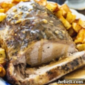 Pork Loin on a platter with roasted potatoes, ready to be carved, showcasing its golden-brown exterior.