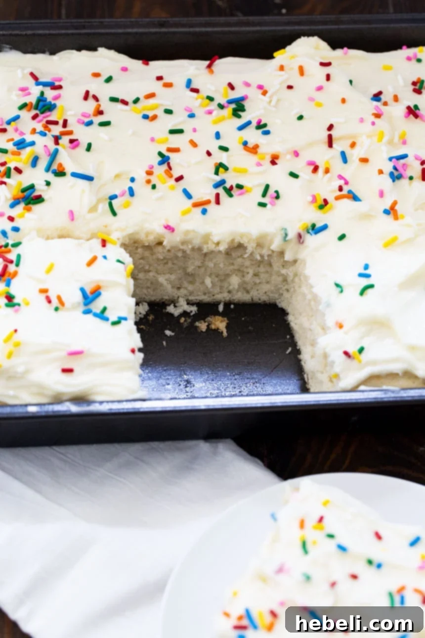 Sheet cake in baking dish with one slice expertly cut out, showcasing its moist layers and smooth icing.