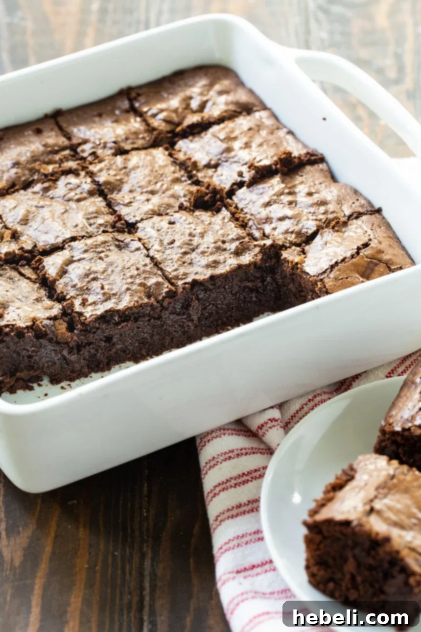 Rich, dark Bittersweet Brownies cooling in a 9-inch square baking dish, highlighting their dense texture and inviting aroma.