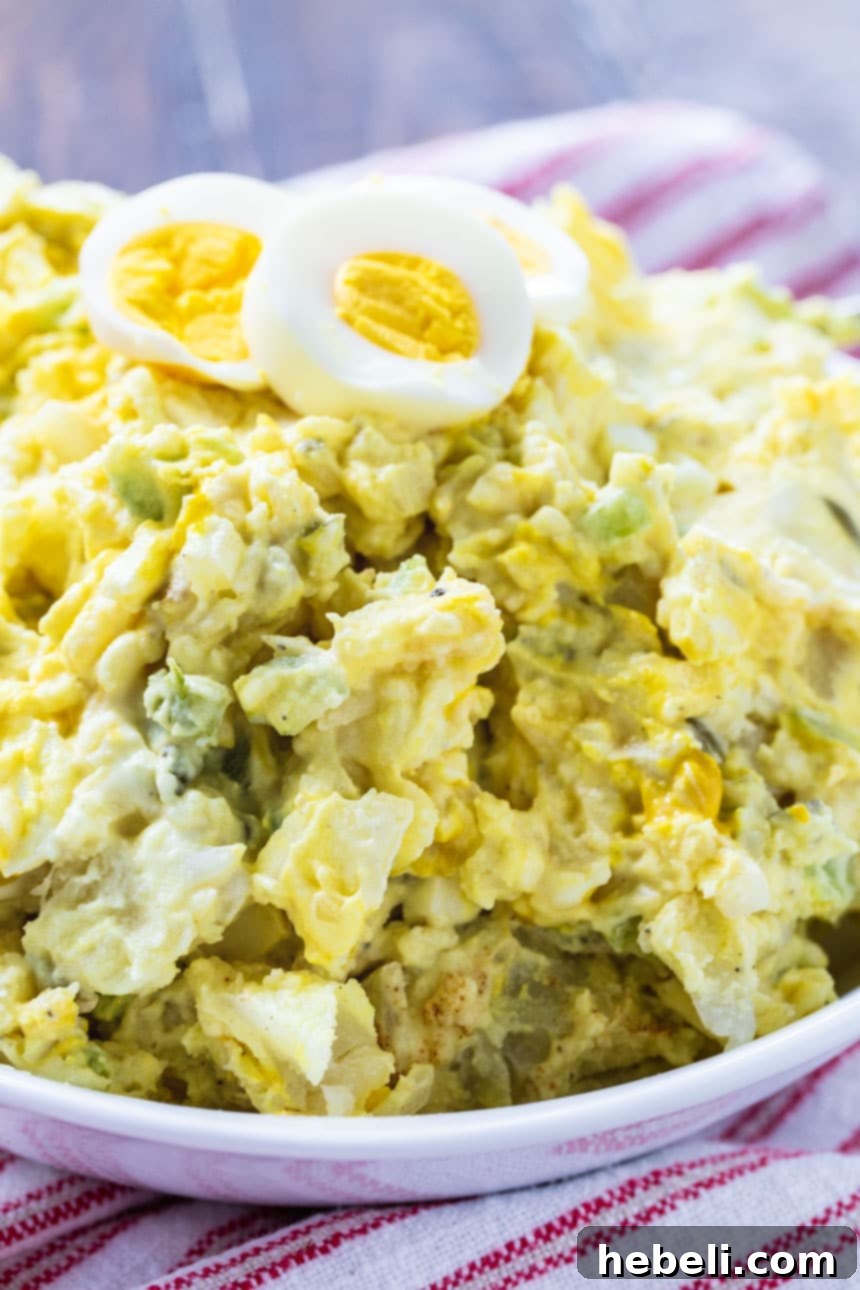 A vibrant, close-up shot of creamy Southern Mustard Potato Salad in a large white bowl, garnished with paprika.