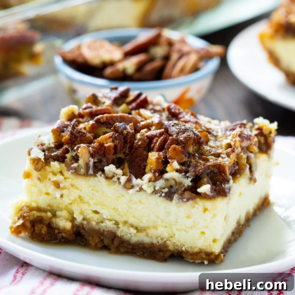 A slice of Pecan Pie Cheesecake Bar on a white plate, showcasing the distinct layers.