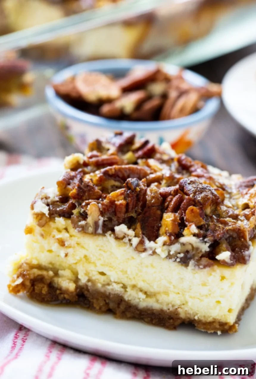 A beautifully presented Pecan Pie Cheesecake Bar on a white plate, with a bowl of pecans in the background.