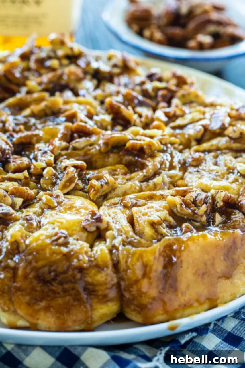 Close-up view of a Bourbon Pecan Cinnamon Roll, showcasing its sticky caramel and abundant pecans.