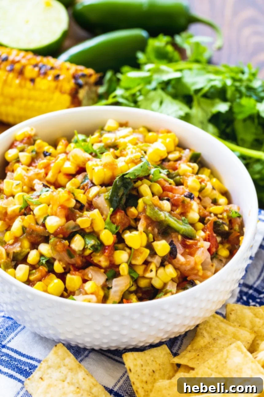 A close-up shot of vibrant roasted corn salsa showcasing the diced peppers, corn kernels, and cilantro in a white serving bowl.
