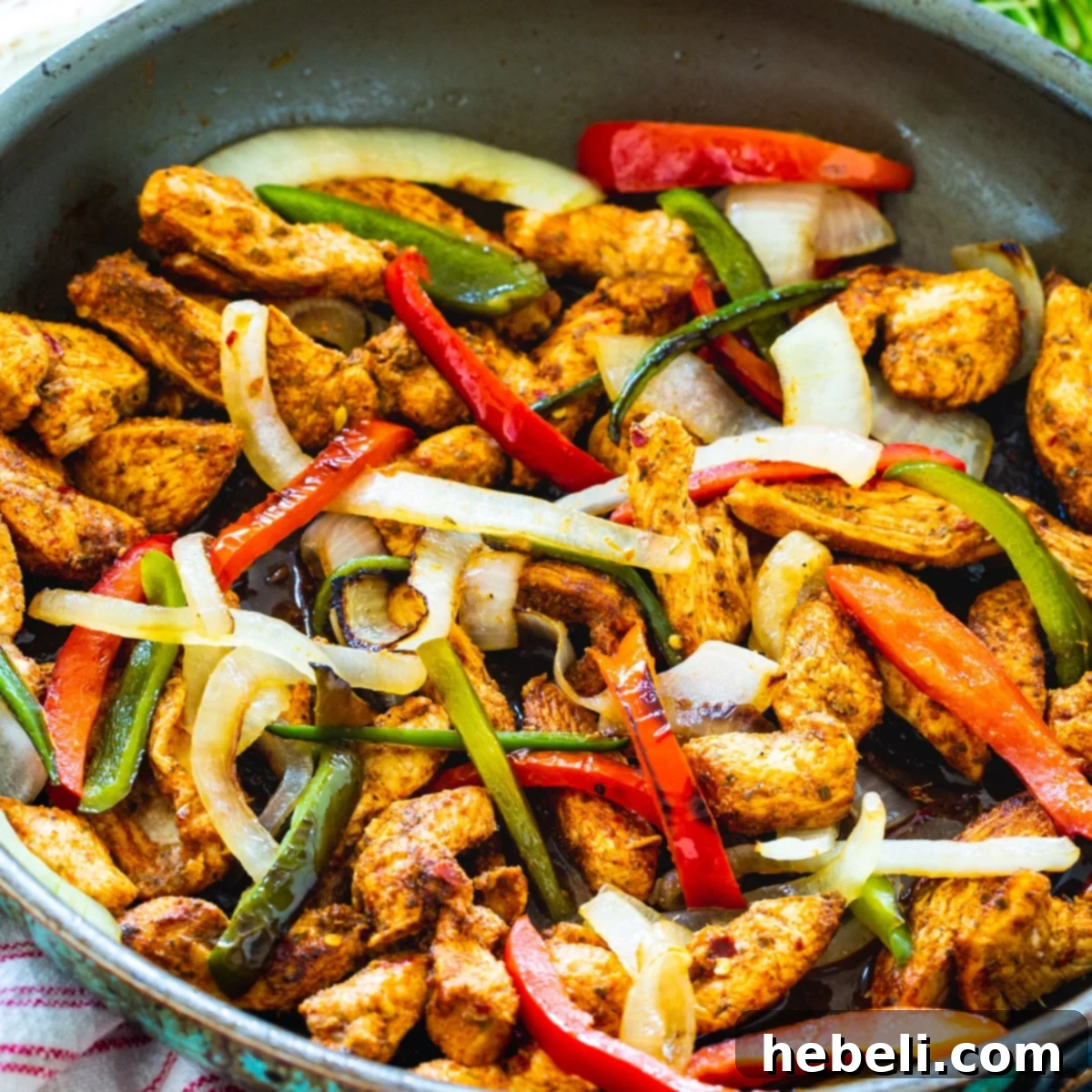 Zesty Sizzling Chicken Fajitas 2 Sizzling Spicy Chicken Fajitas in a cast iron skillet, showcasing vibrant peppers, onions, and perfectly seared chicken strips.