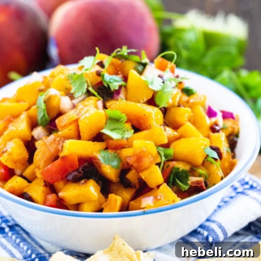 Smoldering Peach Salsa 2 Vibrant Peach Salsa in a bowl, surrounded by fresh, ripe peaches and green cilantro sprigs, ready to be enjoyed.