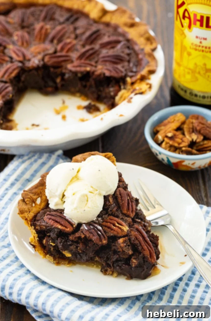 A generous slice of Mocha Pecan Pie on a white plate, with the rest of the pie blurred in the background, highlighting the pie's deep color and intricate pecan top.