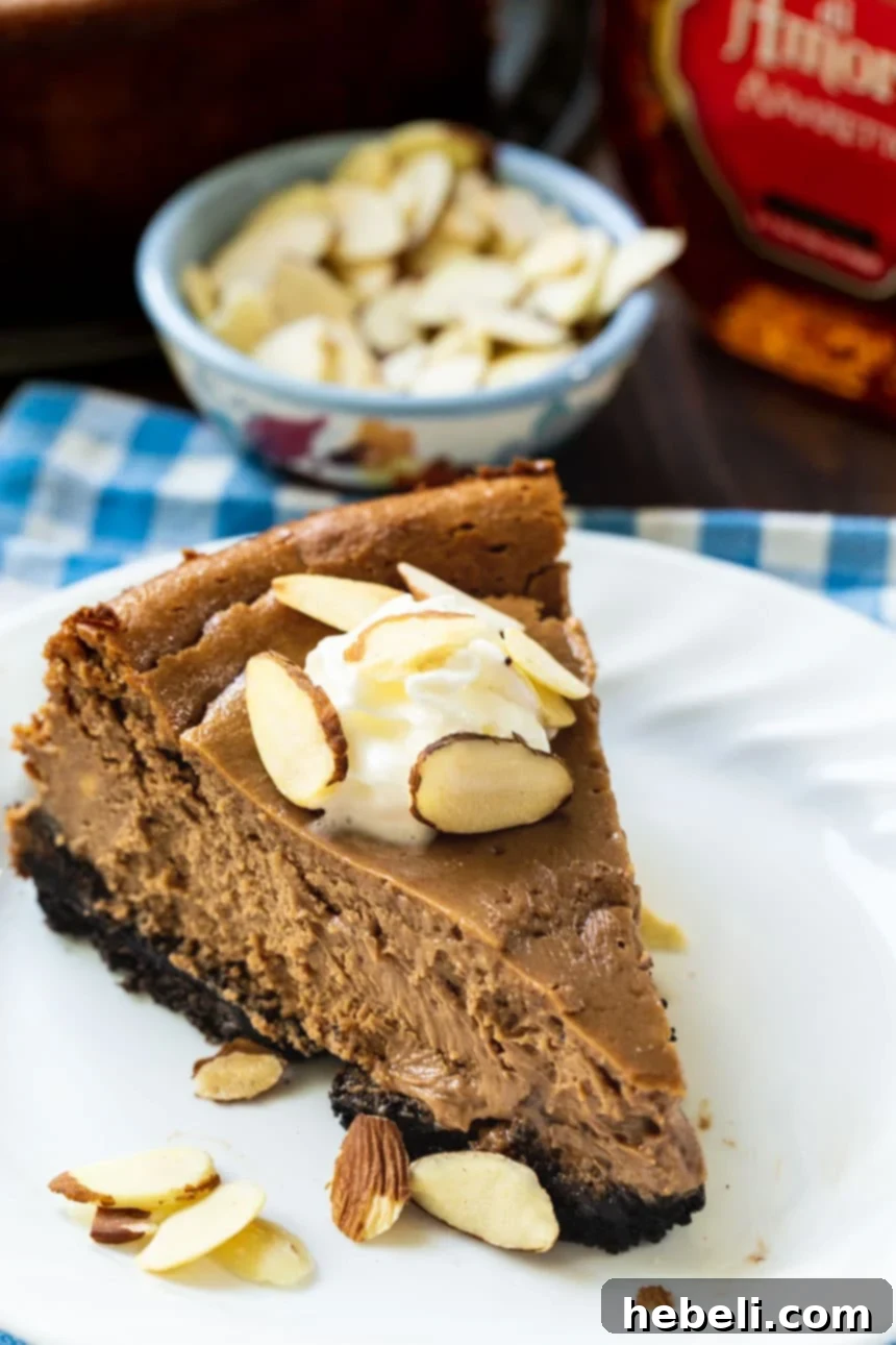 A stunning overhead shot of the full Chocolate Amaretto Cheesecake, generously topped with whipped cream swirls and toasted almond flakes, showcasing its elegant finish.