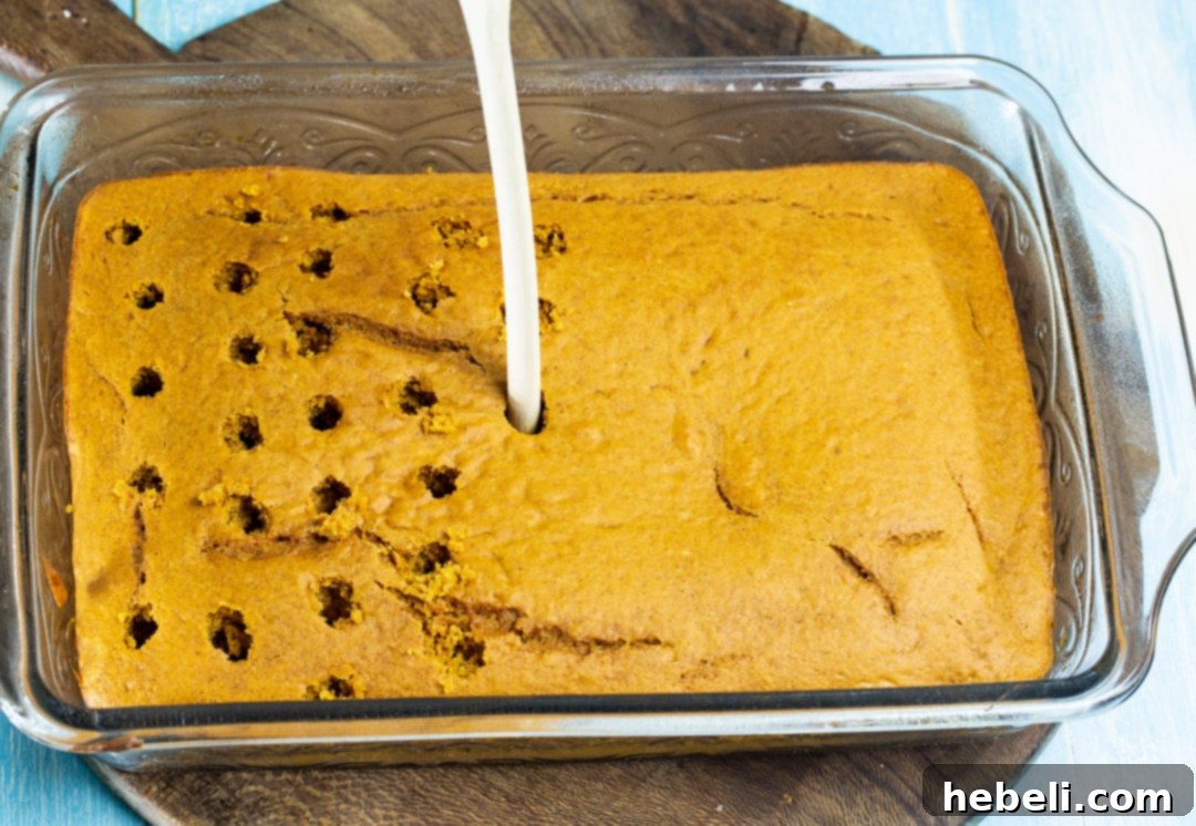 Close-up of a baked cake being poked with the back of a wooden spoon to create holes for the caramel sauce.