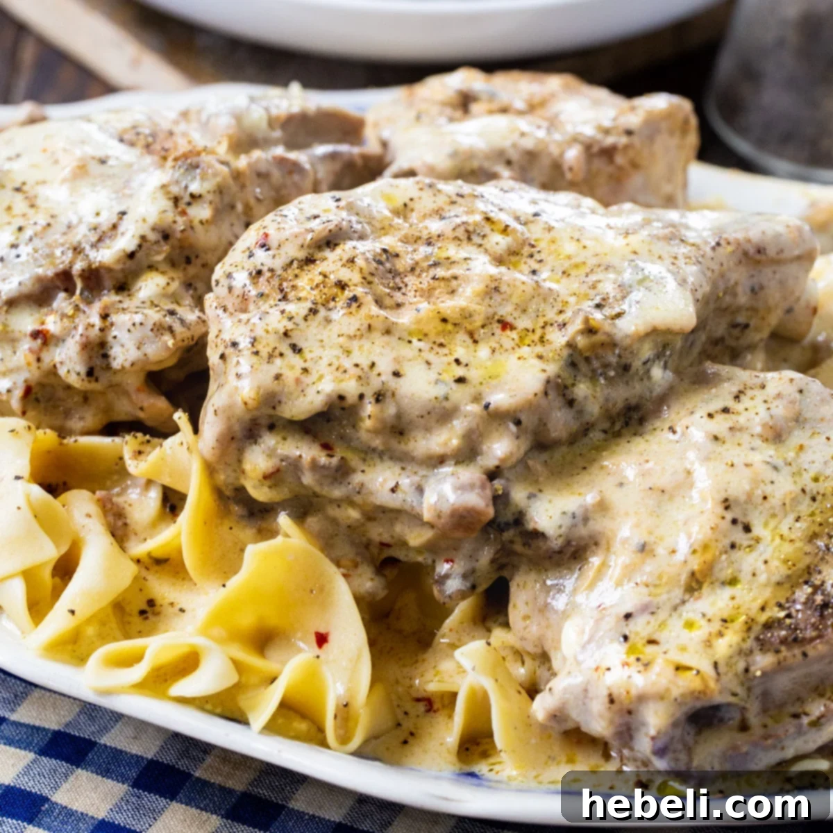 Slow Cooker Creamy Ranch Pork Chops over noodles, garnished with fresh parsley.