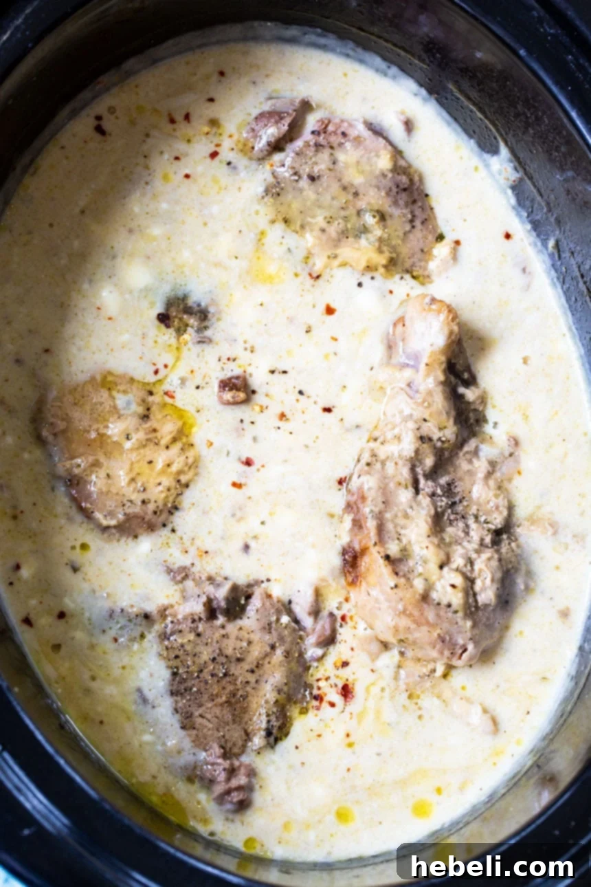 Pork Chops simmering in a creamy sauce in the slow cooker.